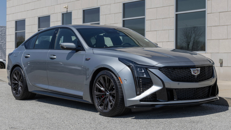 건물 앞에 주차된 은색 Cadillac CT5-V Blackwing의 전면 3/4 모습.