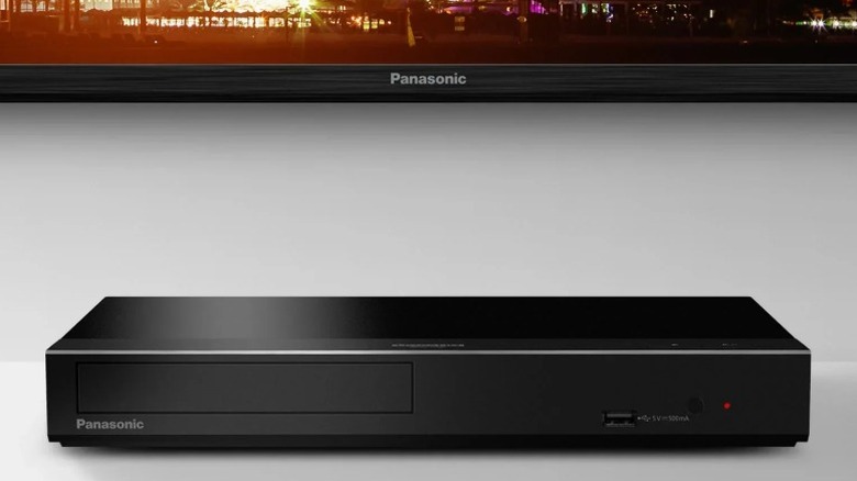 Panasonic TV 아래 흰색 선반에 있는 Panasonic DP-UB450P-K Blu-ray 플레이어