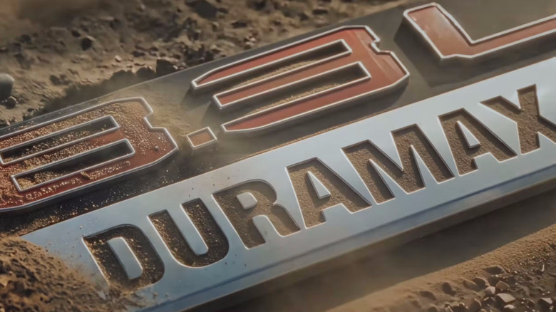 8.3L Duramax 로고가 모래 지형에 부분적으로 덮여 있음