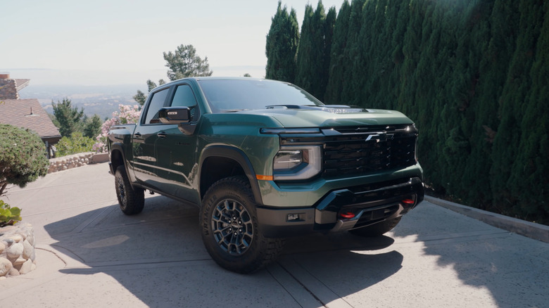 언덕이 많은 진입로에 녹색으로 표시된 2027 Chevrolet Silverado Trail Boss, 전면 3/4 뷰