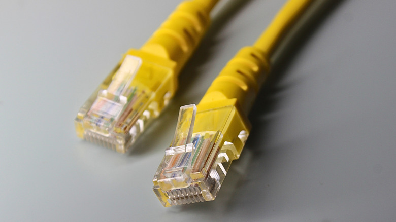회색 배경에 RJ45 커넥터가 있는 노란색 LAN 케이블 2개