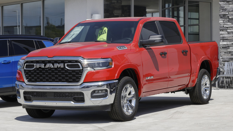 빨간색과 크롬색의 Ram 1500이 대리점 앞에 주차되어 있습니다.