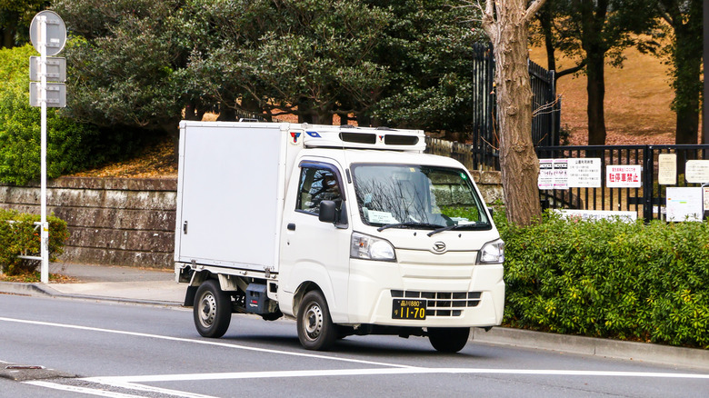 도시 도로를 달리는 흰색 Daihatsu HiJet 냉장고 트럭