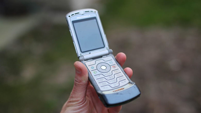 Motorola Razr V3 폴더폰을 들고 있는 손