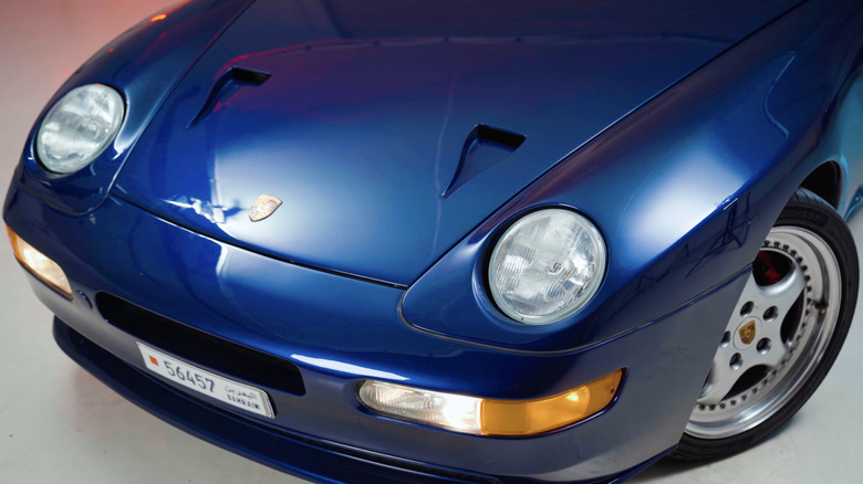 차고의 스튜디오 조명 아래에서 보기 드문 파란색 Porsche 968 Turbo S를 정면으로 클로즈업한 모습.