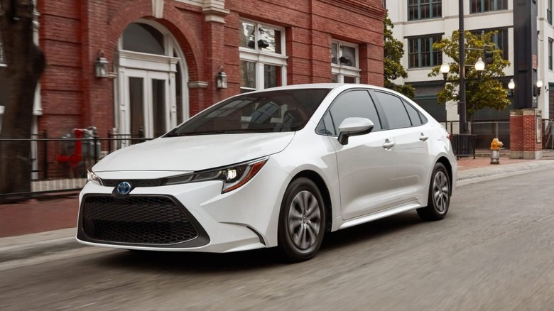 도시 거리를 달리는 흰색 2022 Toyota Corolla Hybrid