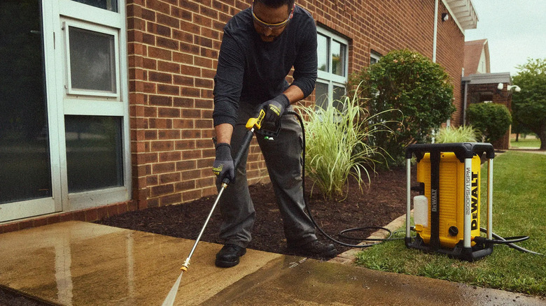 DeWalt 2600 PSI 1.1 GPM 전기 작업장 고압 세척기를 사용하여 집 앞 통로를 청소하는 남성
