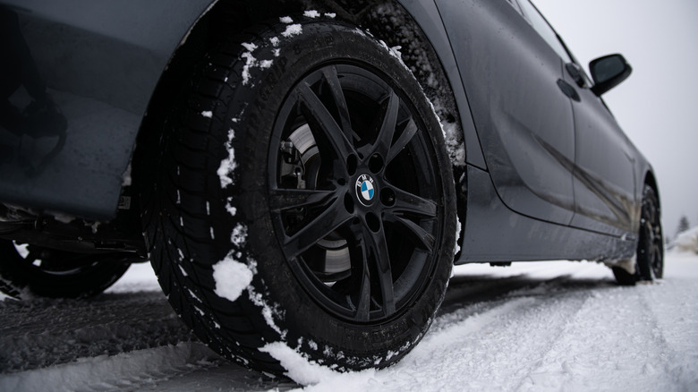 눈 속에서 굿이어 타이어를 장착한 짙은 회색 BMW의 클로즈업.